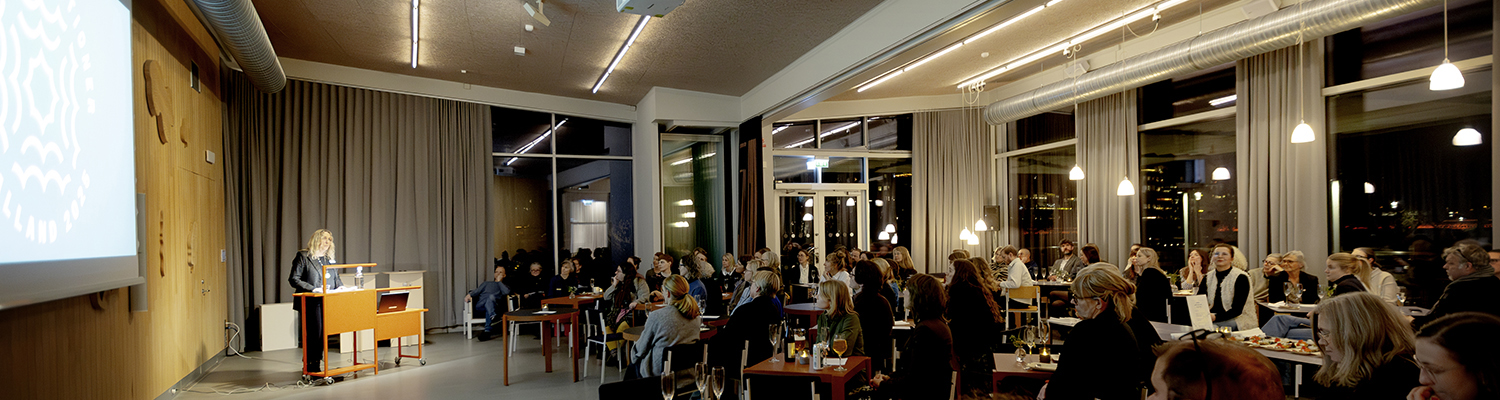 Invigningstalare och sittande publik i en stor lokal.