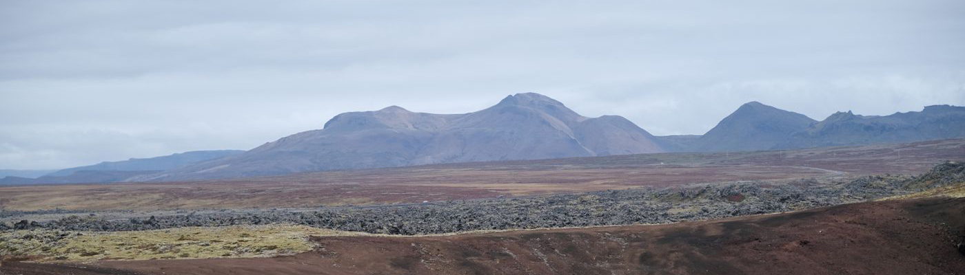 Kargt landskap på Island. Vid horisonten syns berg.